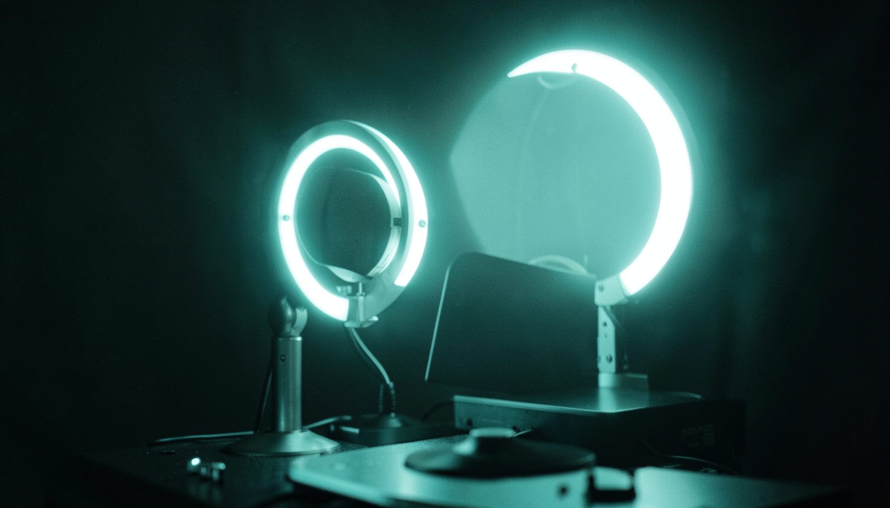 A dimly lit streaming setup with a glowing ring light and microphone against a dark background, moody and modern