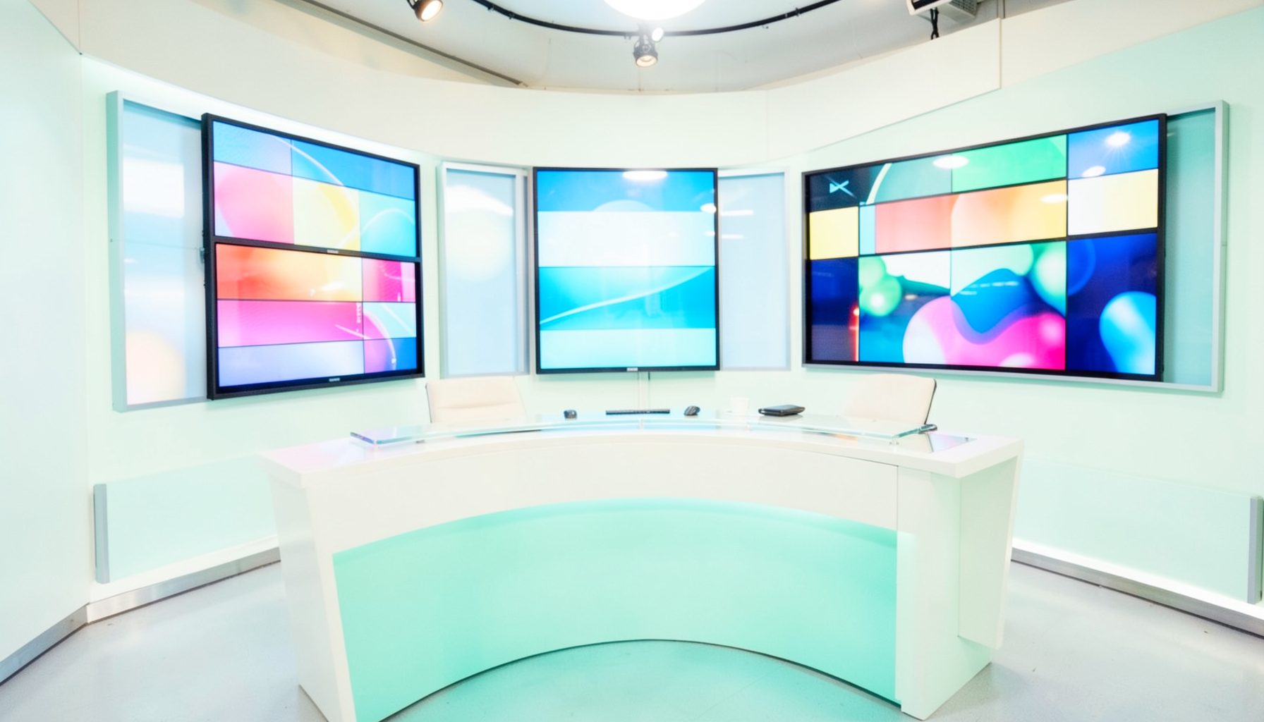 A warmly lit television studio set with colorful screens and a curved desk, bright and inviting