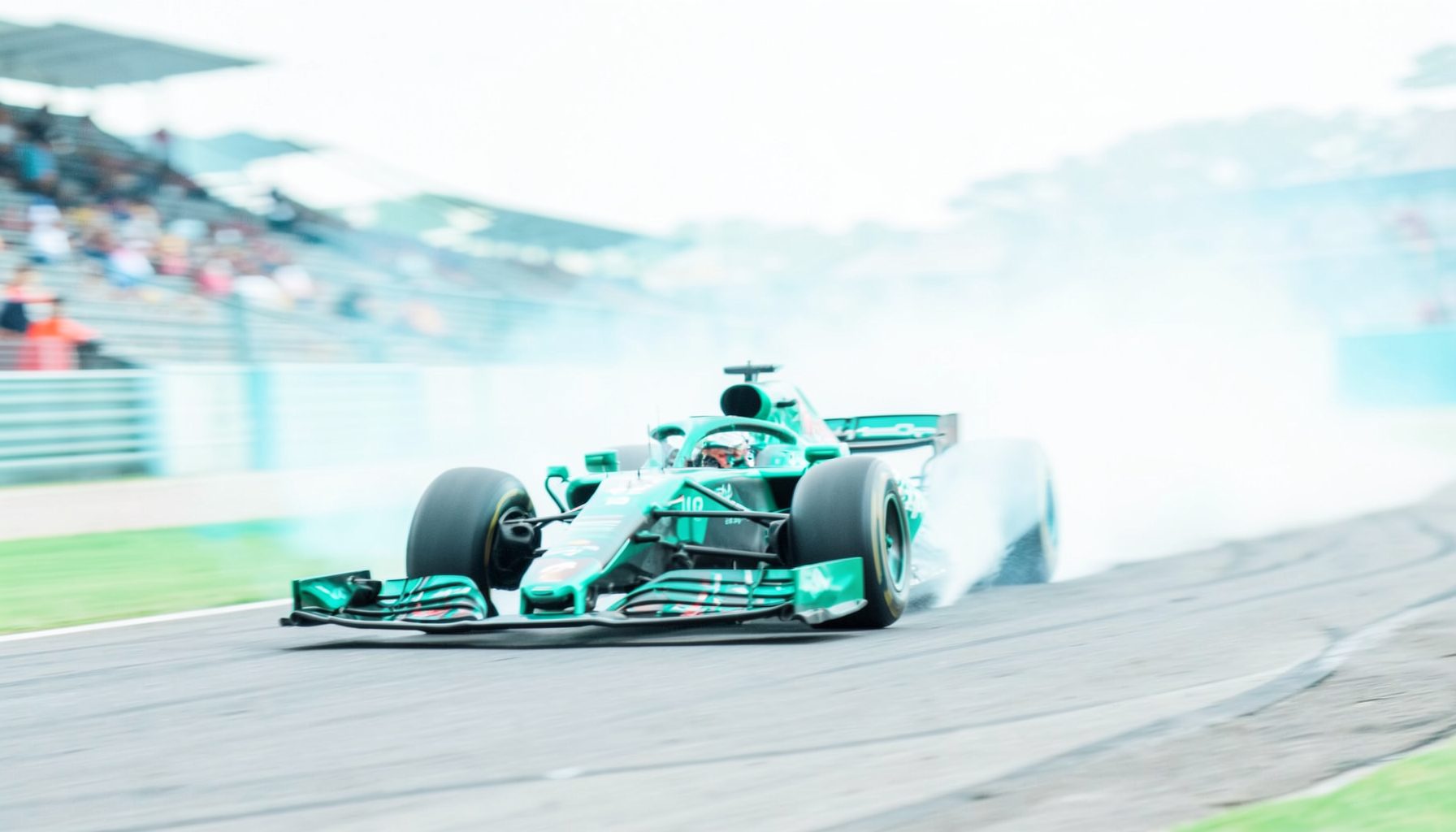 Formula One car speeding through a corner, blurred grandstands and tire smoke, vibrant racing livery against grey asphalt