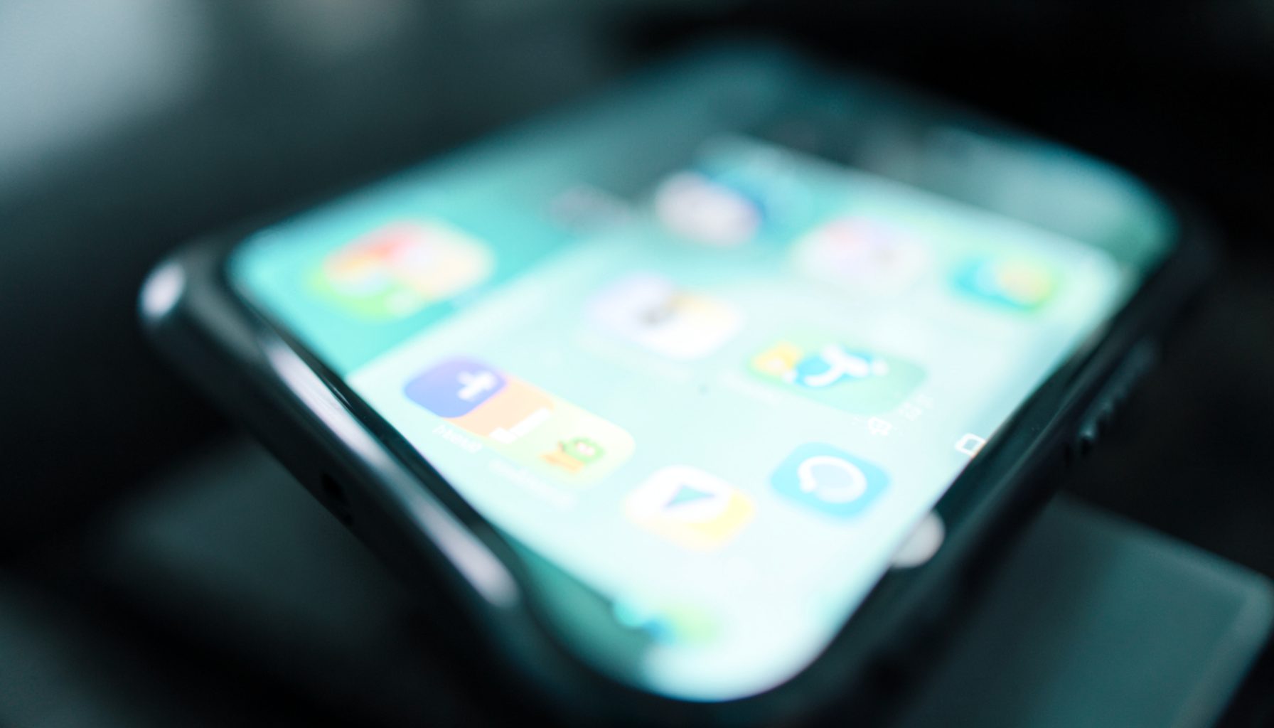 Close-up of a smartphone screen glowing with colorful app icons against a dark blurred background, bright and modern