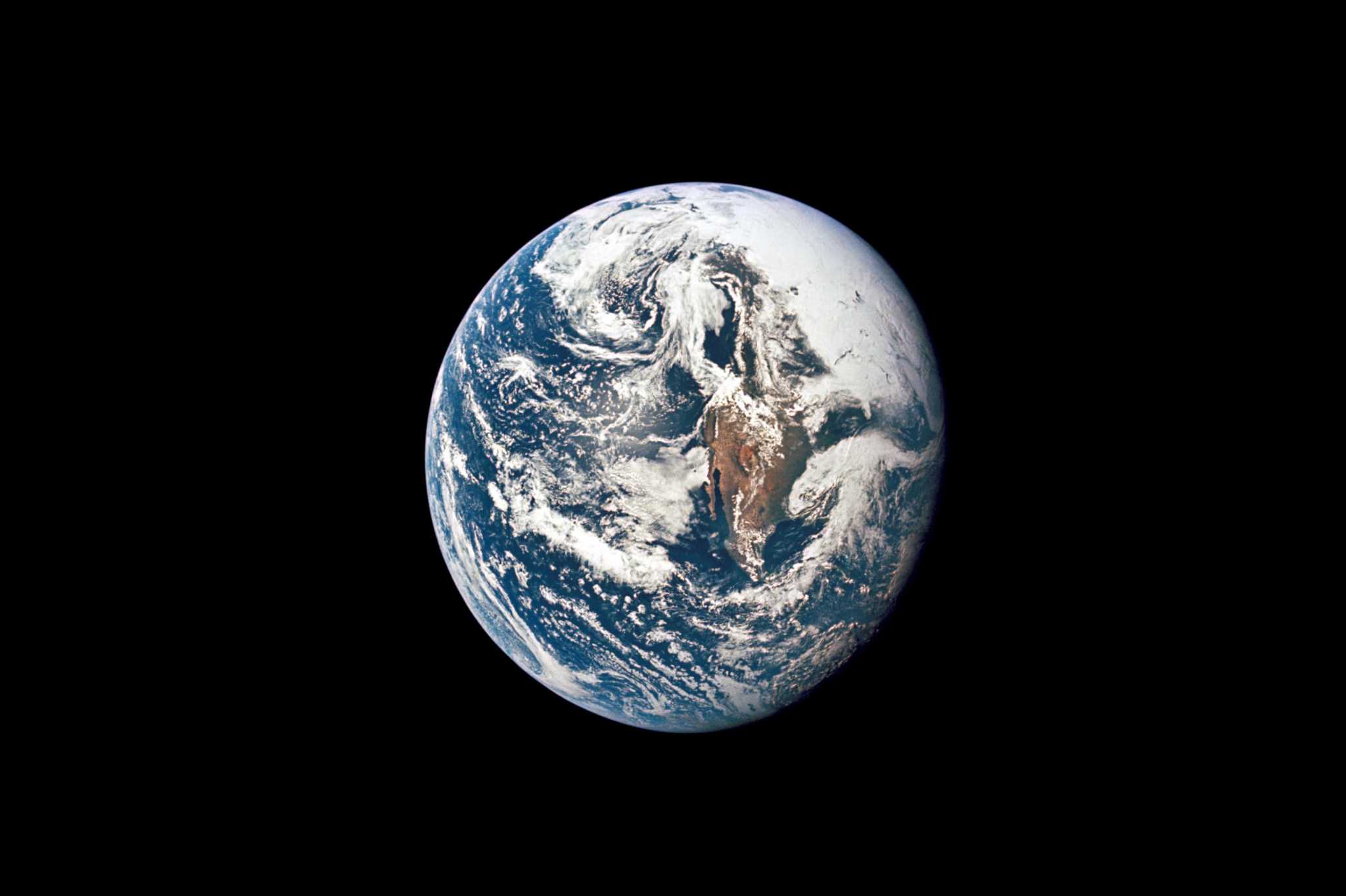 A view of a blue and white planet against a black background, showing swirling clouds and landmasses, calm cosmic mood.